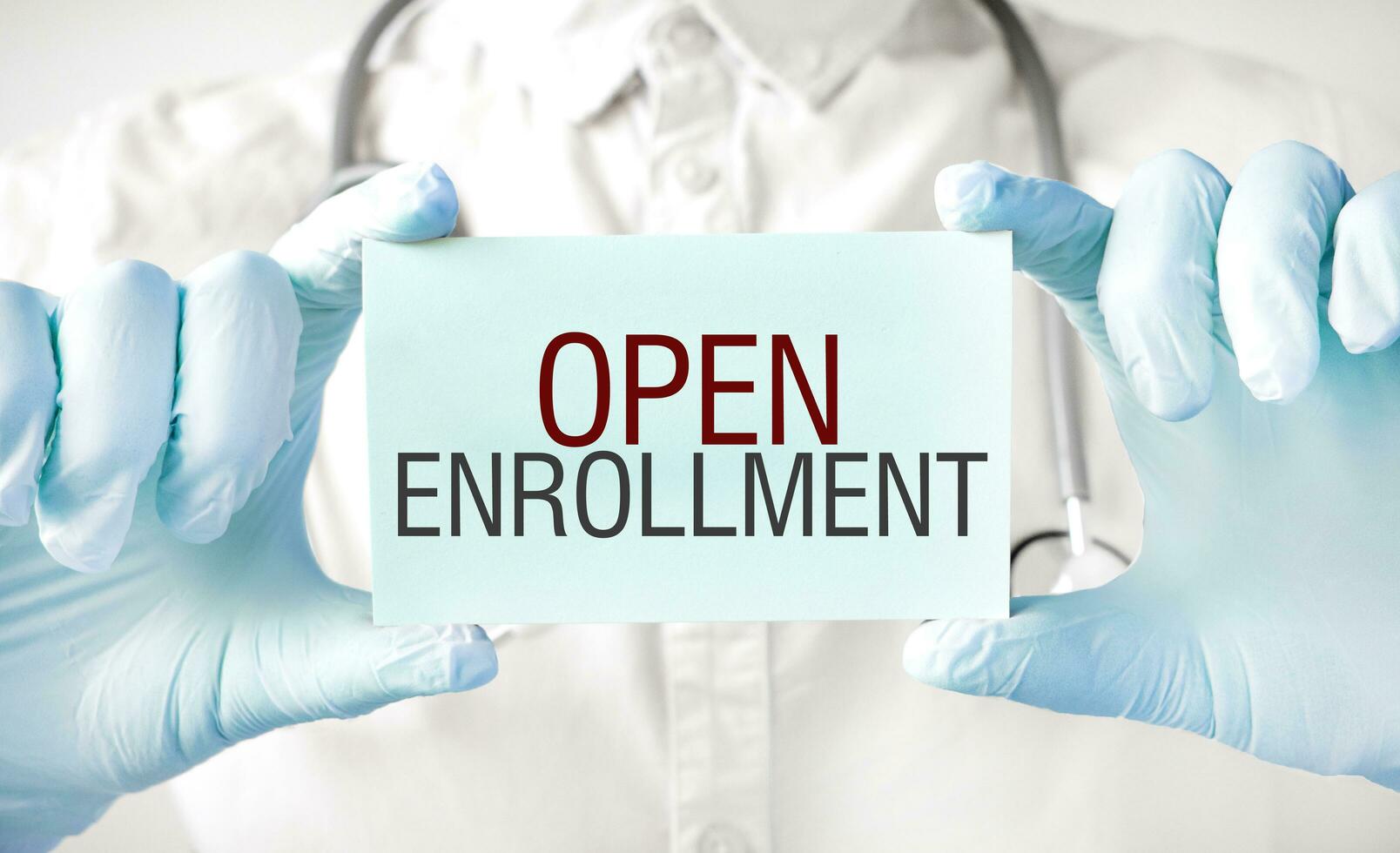Doctor holding card in hands and pointing the word OPEN ENROLLMENT photo