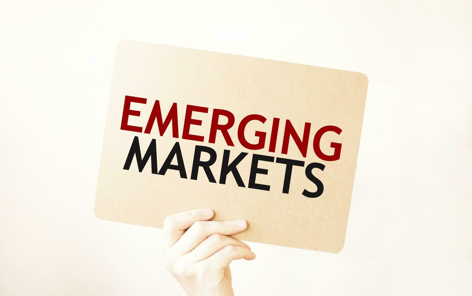 Closeup Business man hand holding show blank paper sheet mock up empty white board space for shouting text rule or protest word. Text EMERGING MARKETS photo