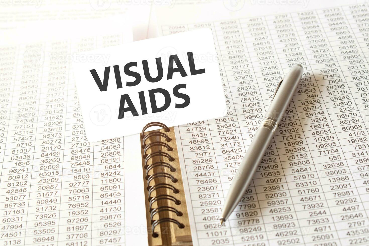 Text VISUAL AIDS on paper card, pen, financial documentation on table - business, banking, finance and investment concept. close up of stock market chart. photo