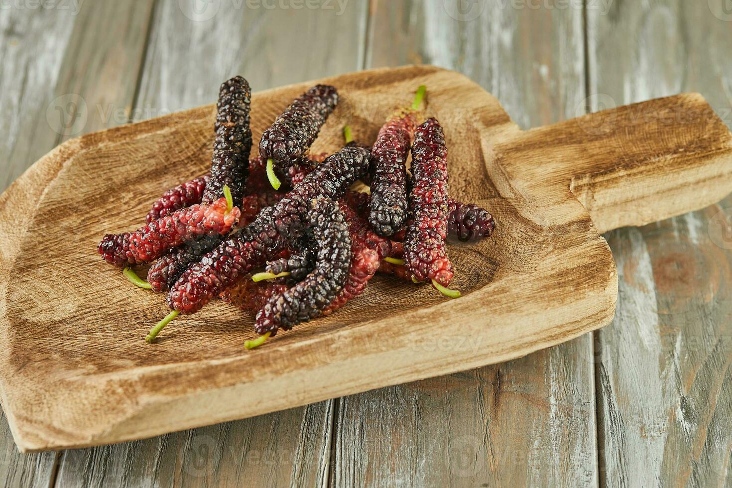 Afghan mulberry black and red on wooden scoop on gray wooden background photo