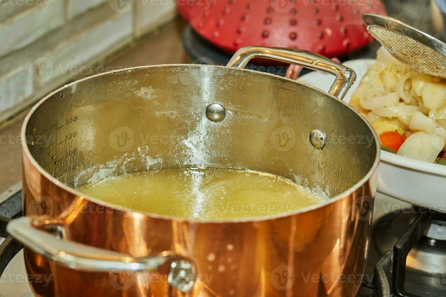 Chicken broth in copper saucepan on gas stove photo