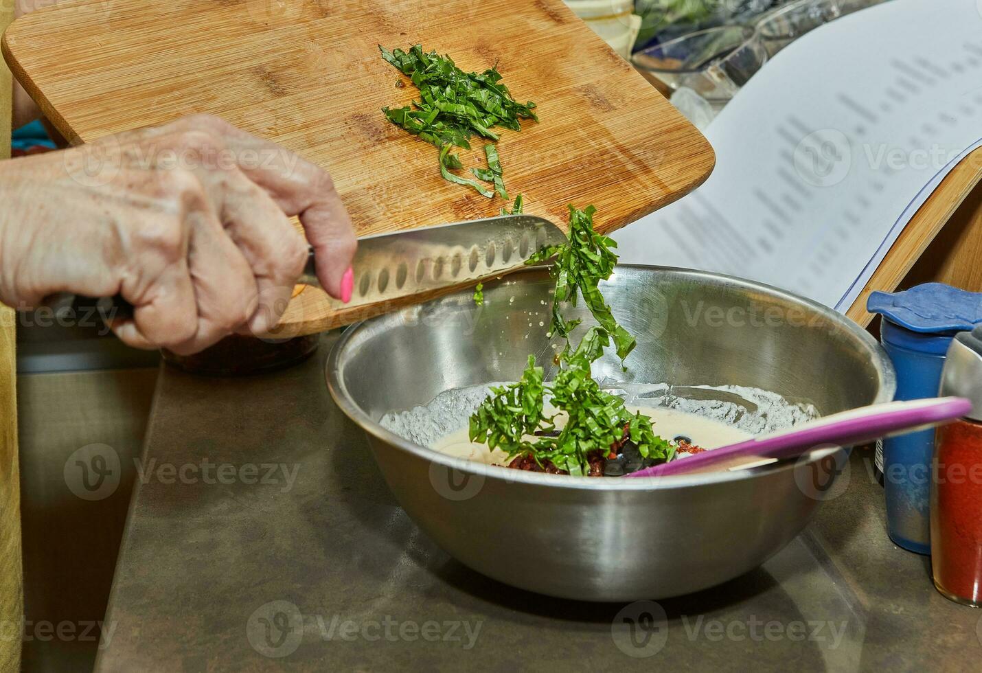 Chef throws basil leaves on wooden cutting board with knife into dish photo