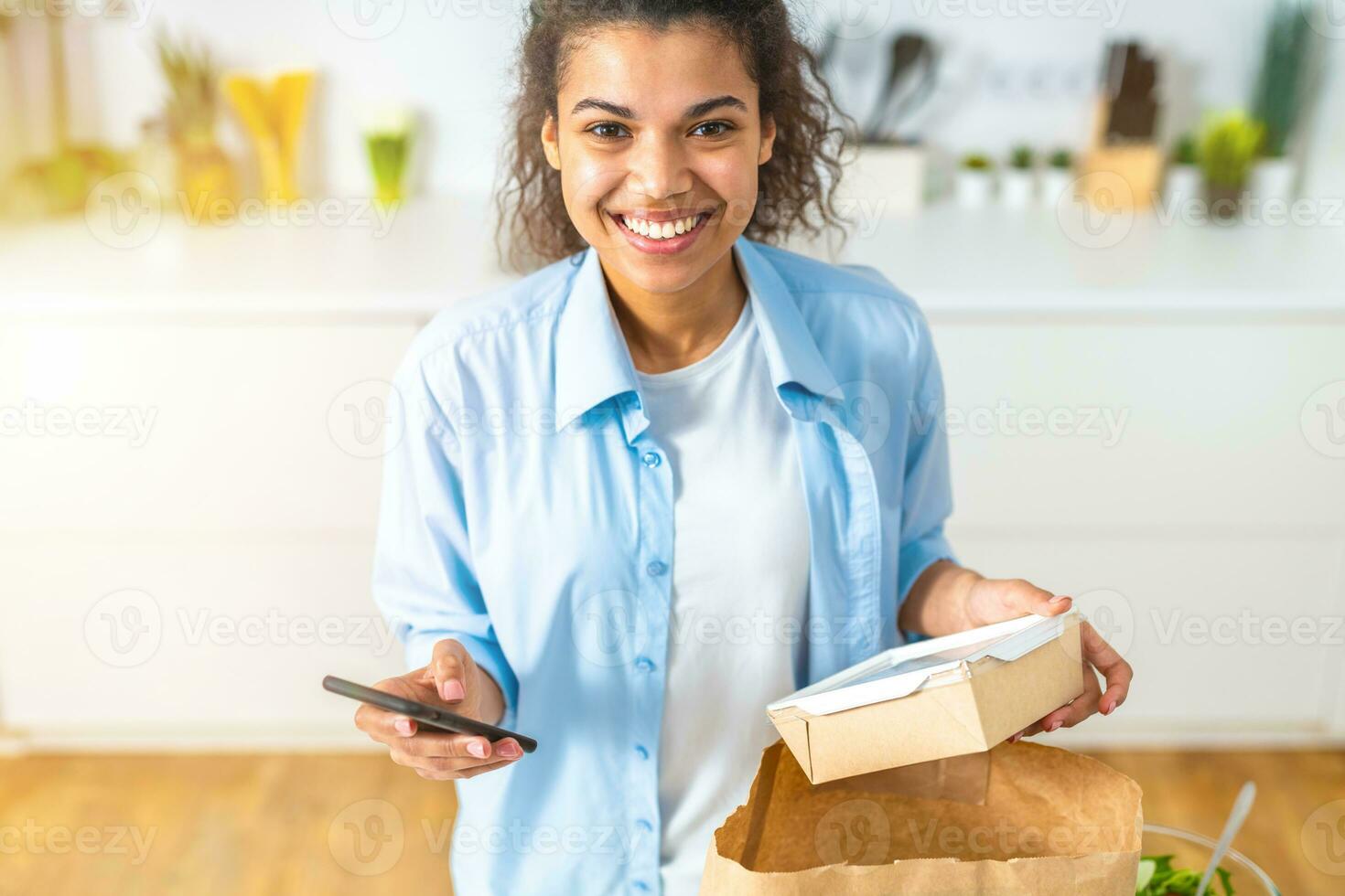 Smiling woman with a shopping bag ordered online via smartphone and delivered directly at home photo