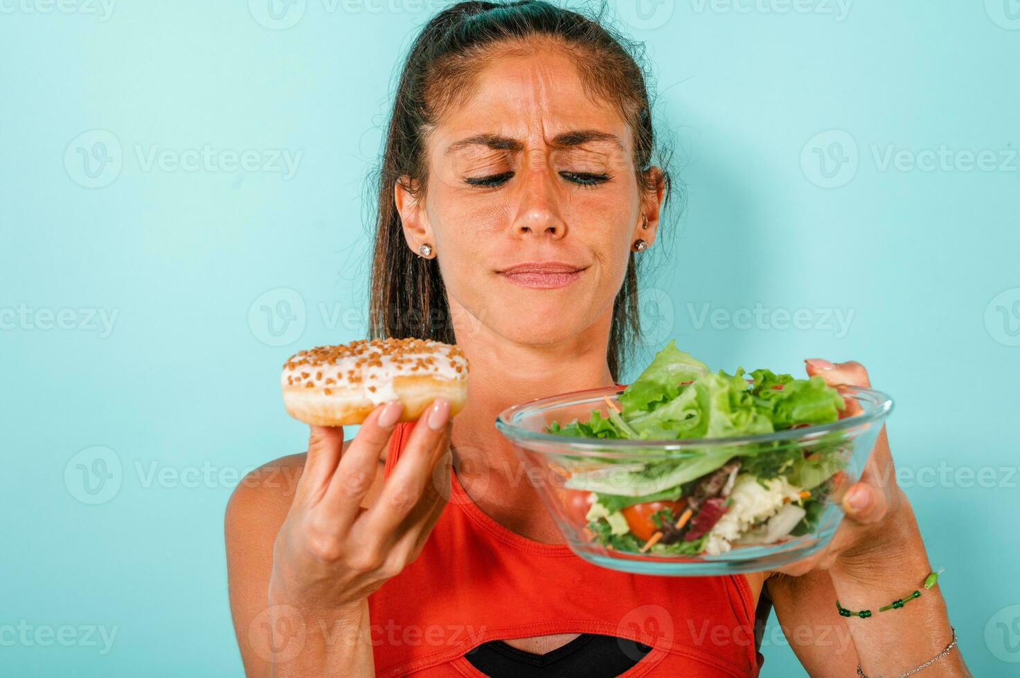 Woman thinks to eat donuts instead of a salad photo