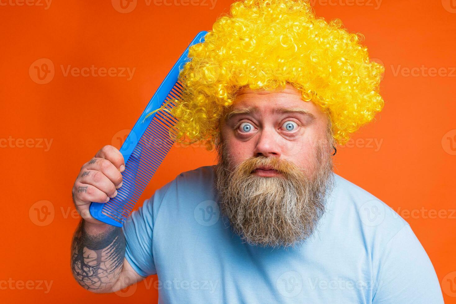 Amazed funny man with tattoos has a big comb in hand photo
