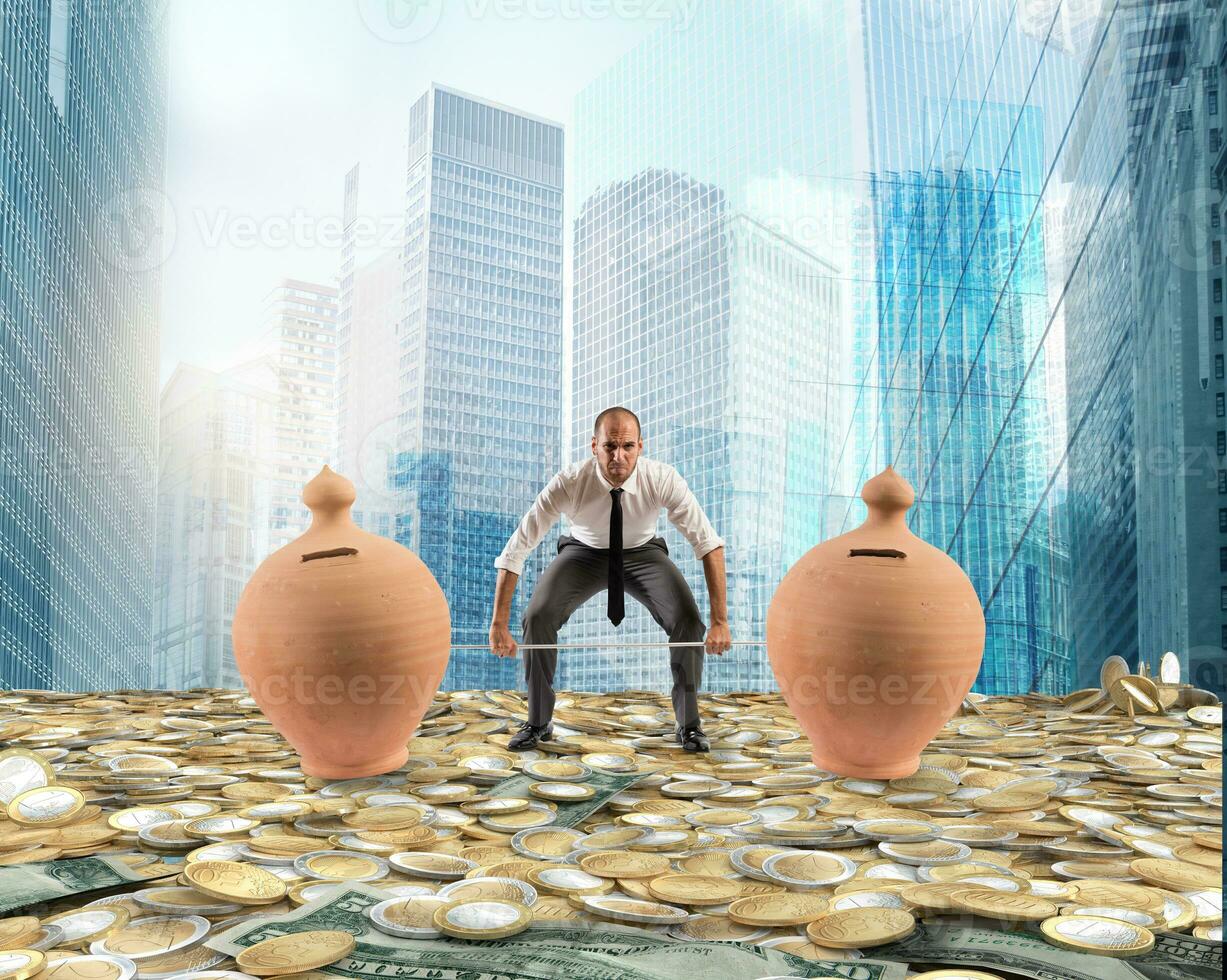 Powerful and determined businessman trains with a barbell with piggy banks photo