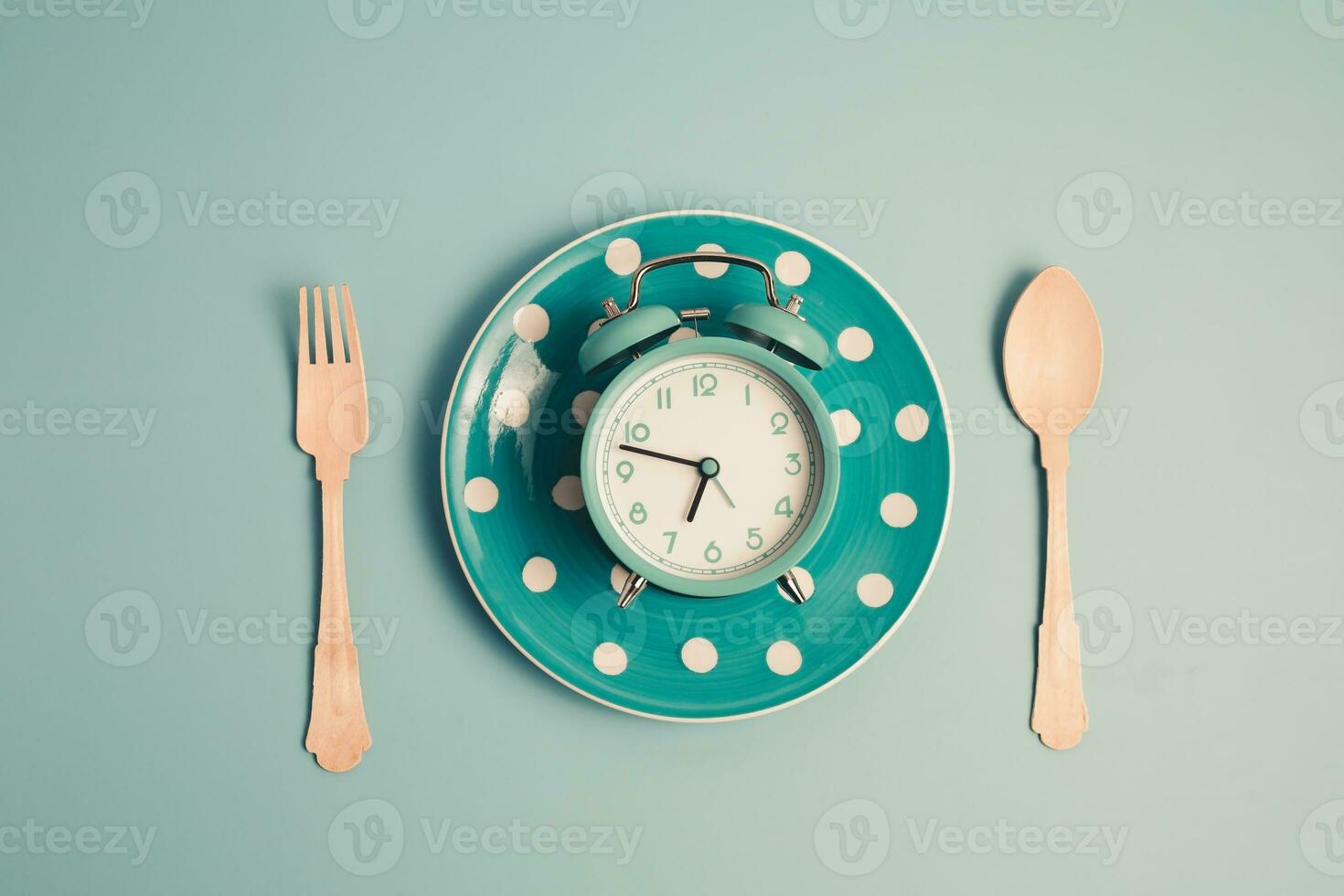 un alarma reloj en un vacío plato y cuchillería conjunto foto
