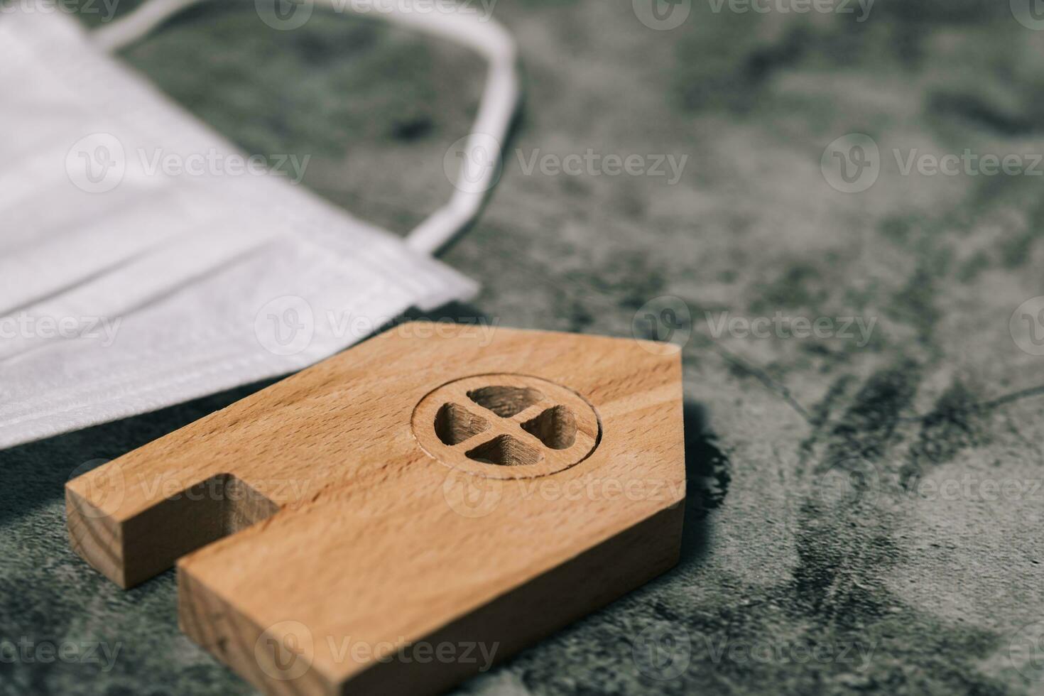 Wooden house model with hygiene face mask on dark background photo