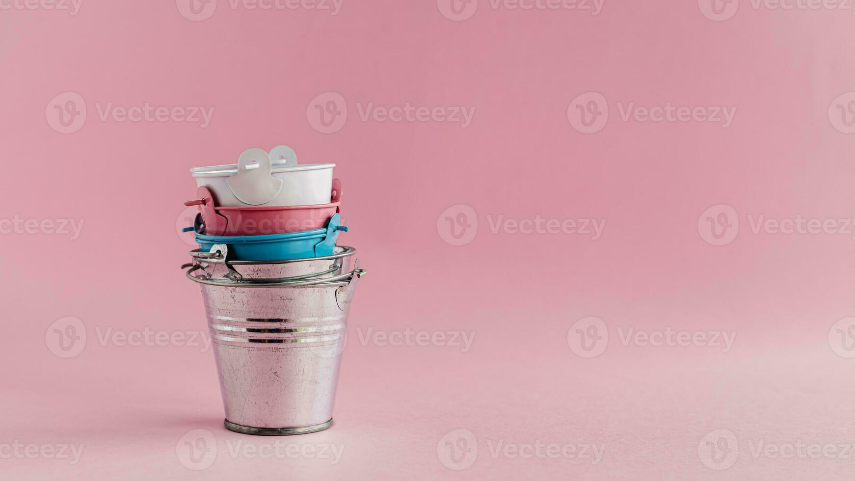 Mini colored tin pails or buckets on pink background photo