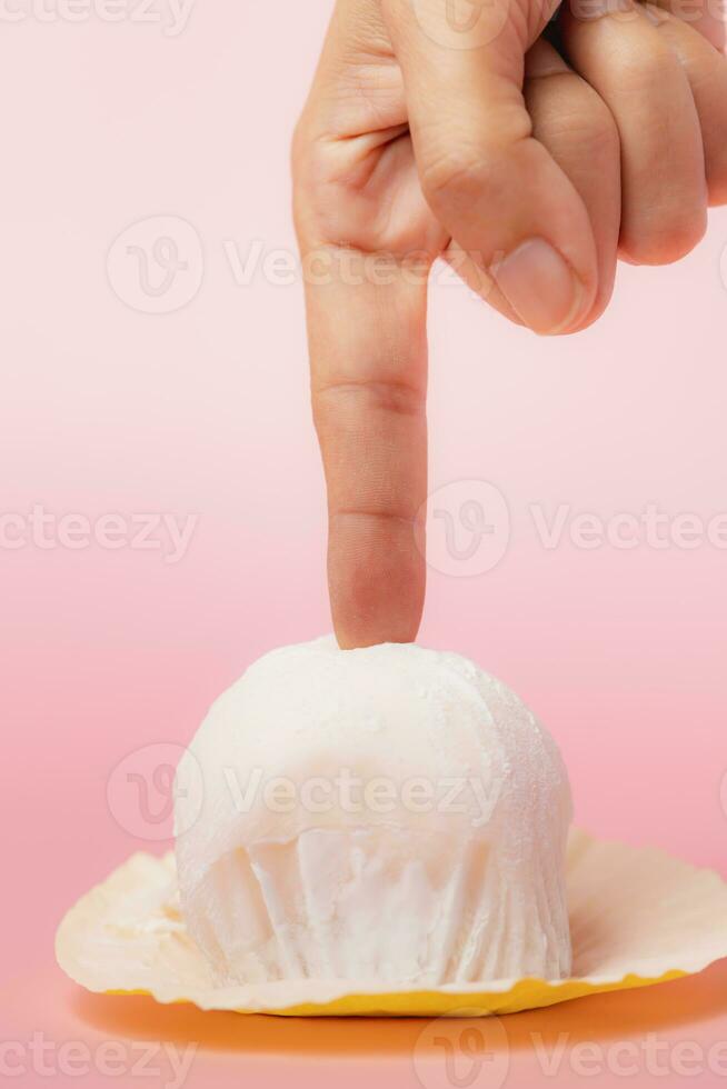 Hand touching delicious strawberry daifuku, Japanese rice cake against pink background photo