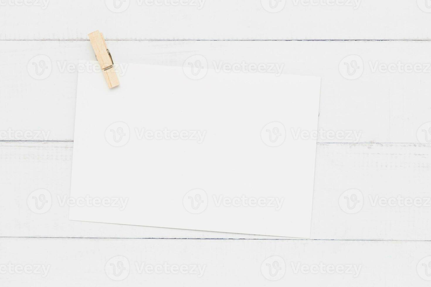 White paper card with wooden clamp on white table background for wedding invitation card design and writing or printing on. photo