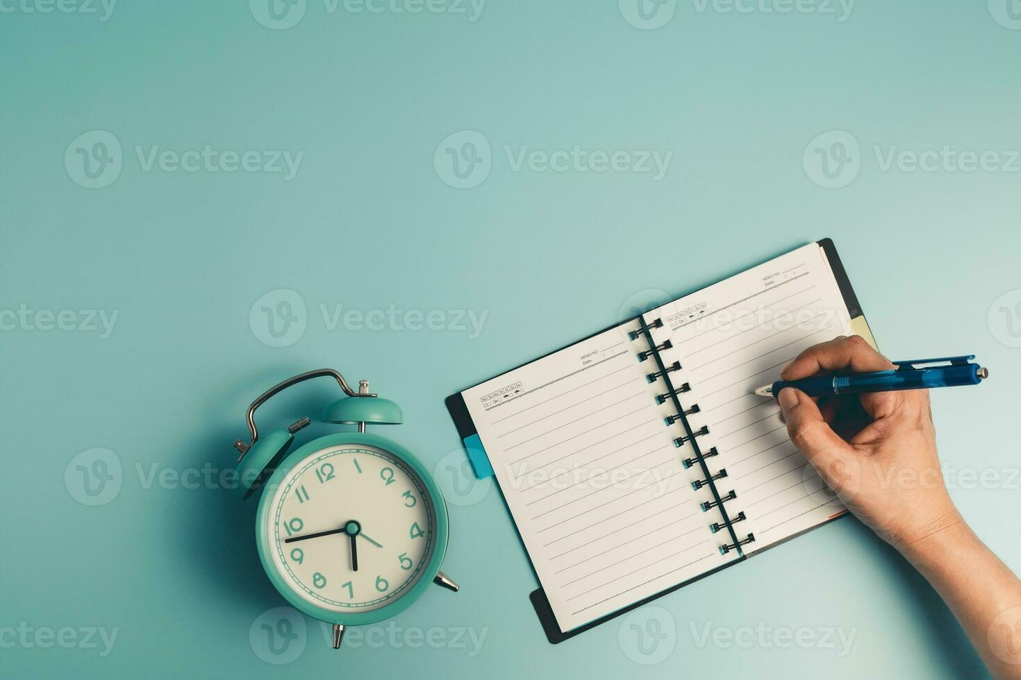 Hand writing on a dairy notebook with an alarm clock photo