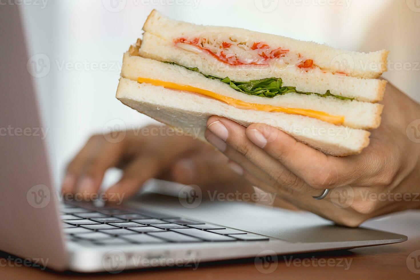 Hand holding a delicious sandwich while working photo