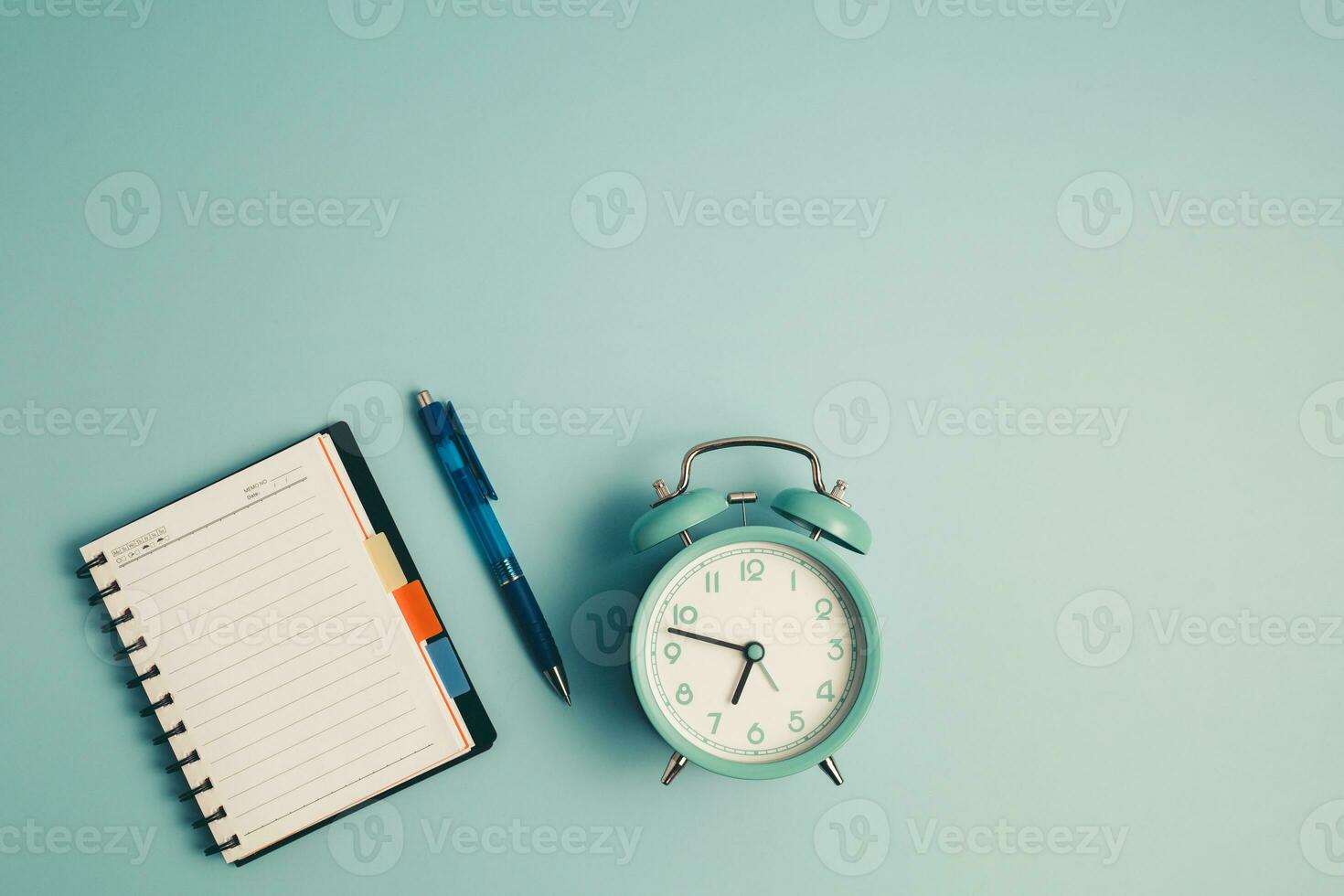 An alarm clock with a diary notebook and others work and educational materials photo