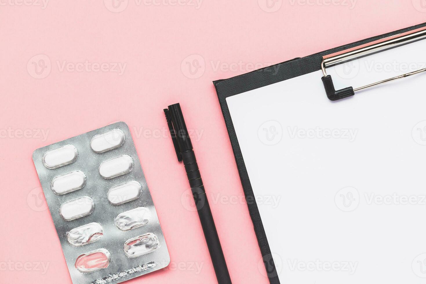 Clipboard with paper, black pen and blister pack of medicine pill on pink background for medical and healthcare concept photo
