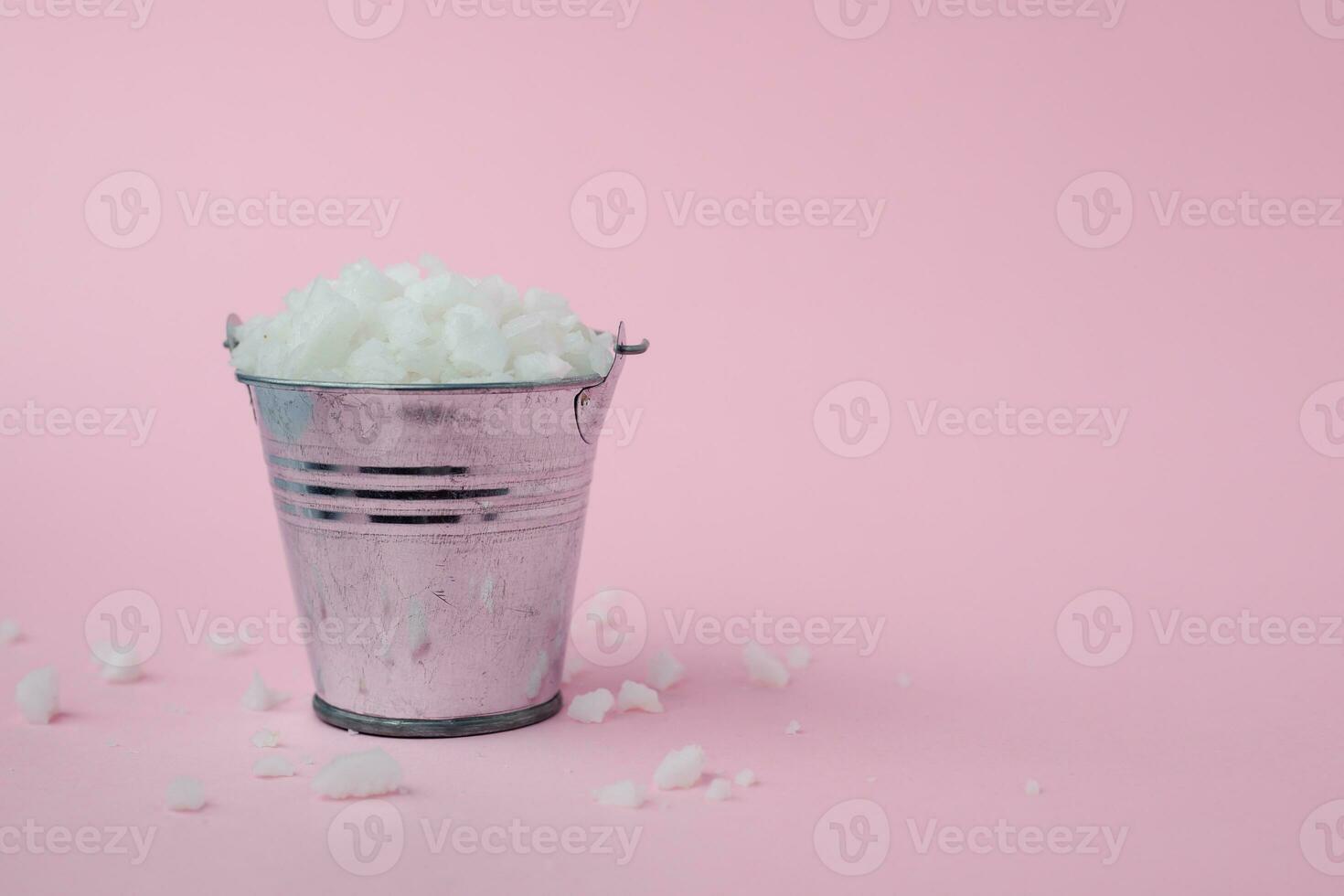 Sea salt in a tin bucket on pink background photo