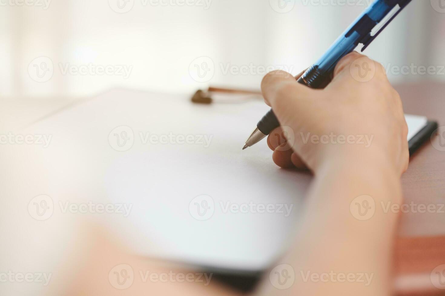 mano participación un bolígrafo y escritura alguna cosa en el cuaderno foto