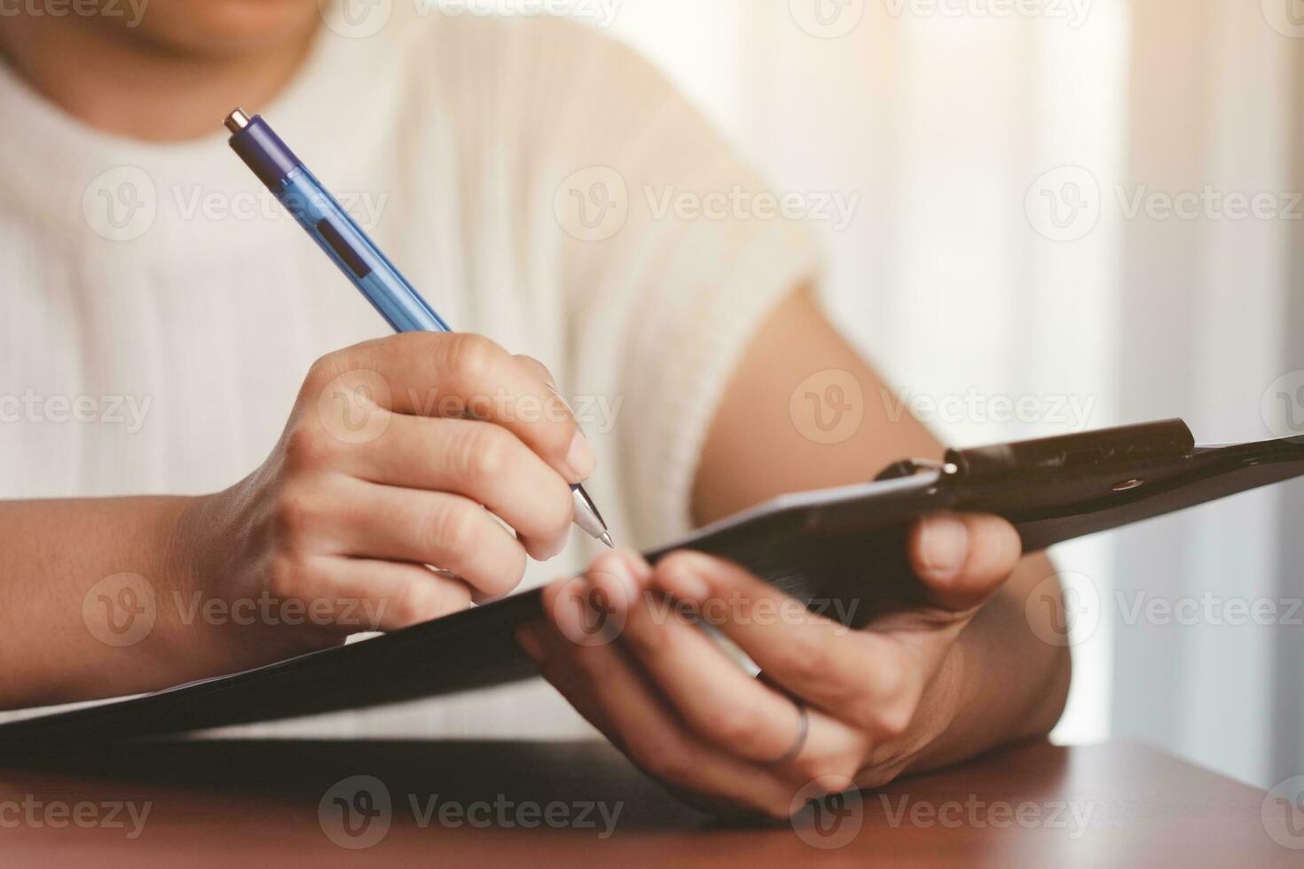 asiático mujer mano participación un bolígrafo y escritura alguna cosa en el cuaderno foto