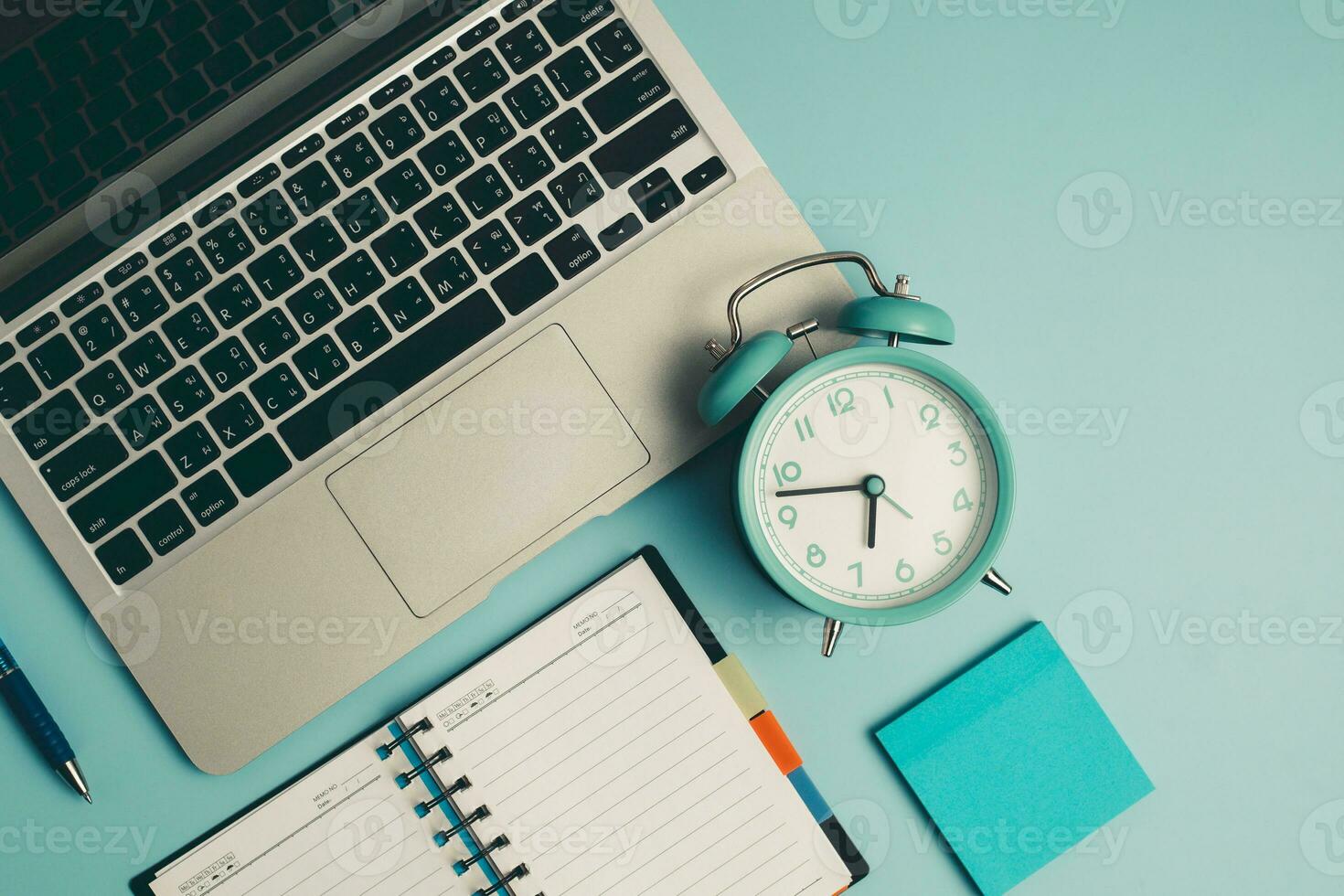 Laptop with an alarm clock, a diary notebook and others work and educational materials photo