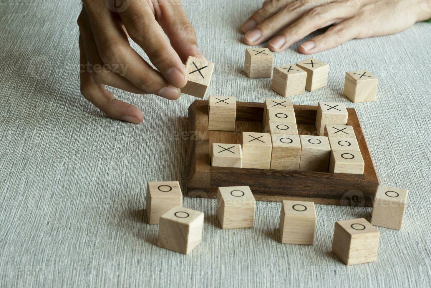 Tic tac toe game made of wooden blocks with hand player photo