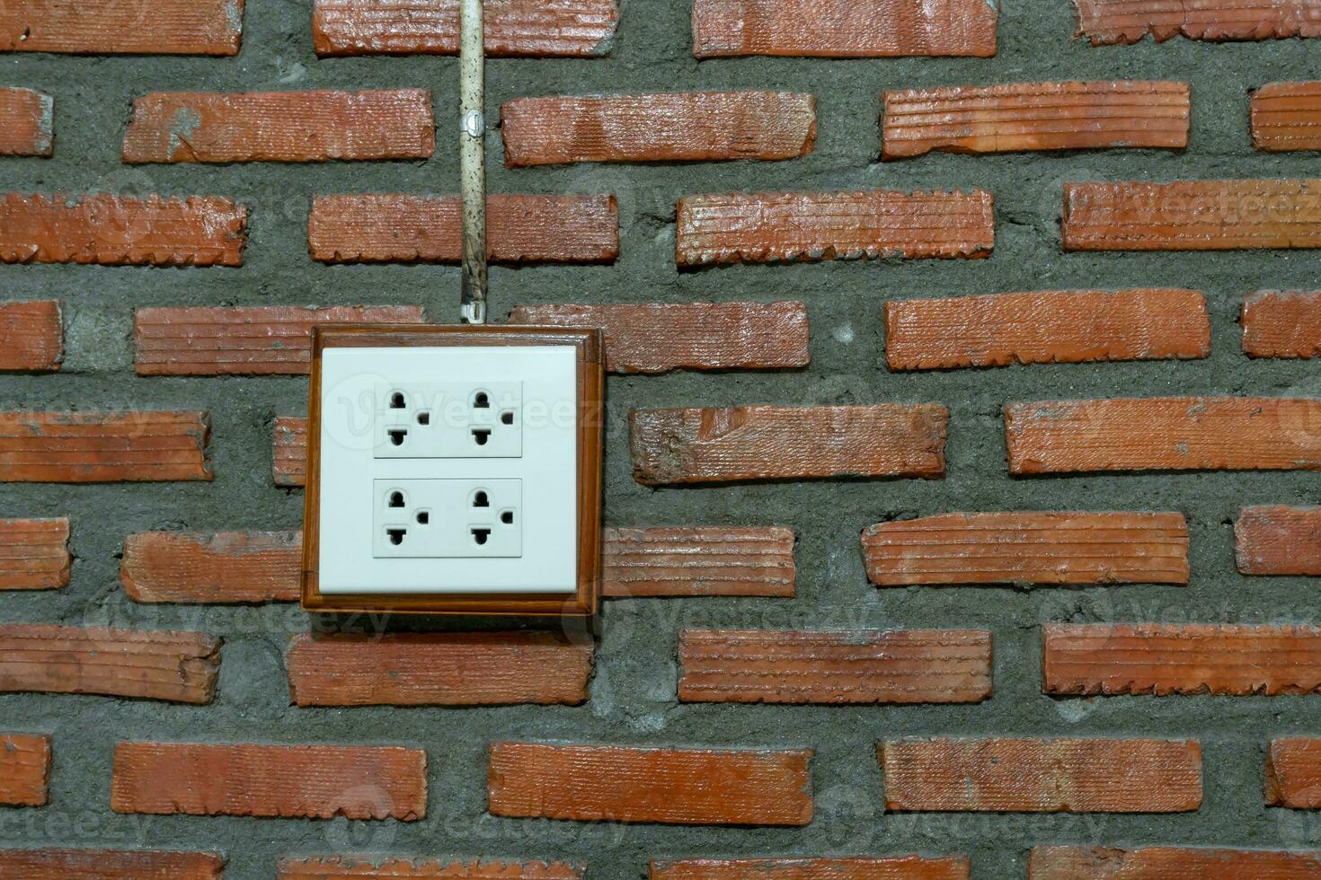 White socket installed on orange brick wall in hotel or resort room. photo