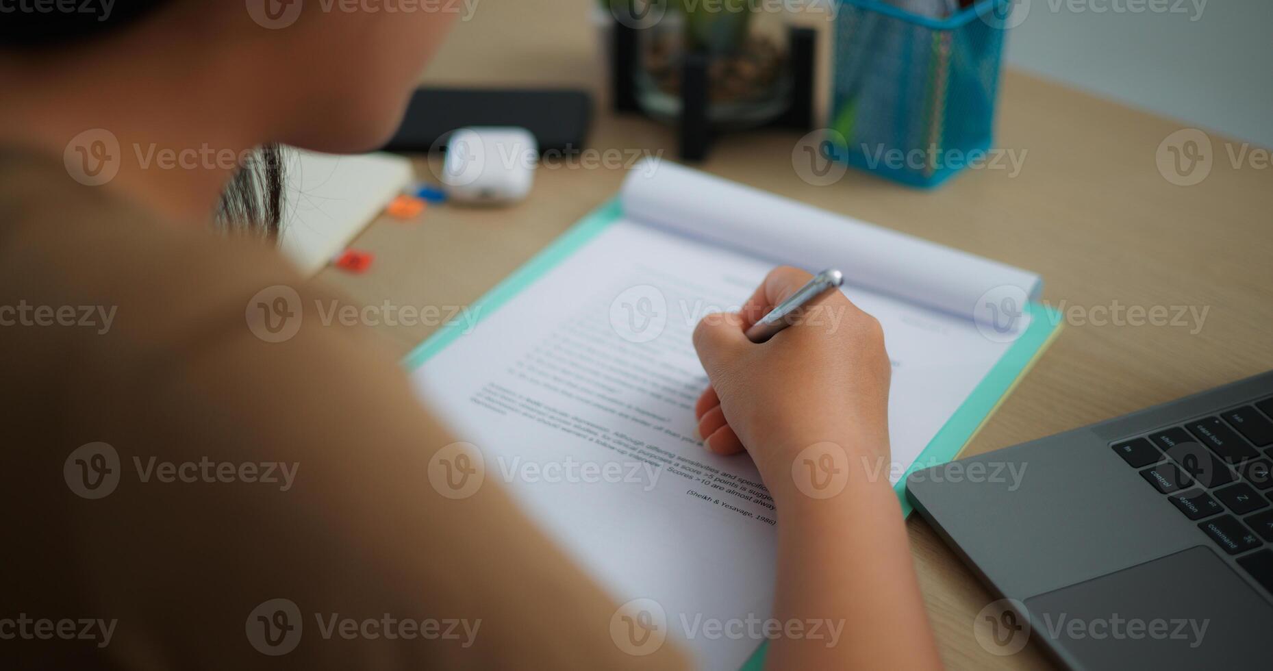 joven asiático mujer trabajando con un ordenador portátil y escritura en papel en un escritorio foto