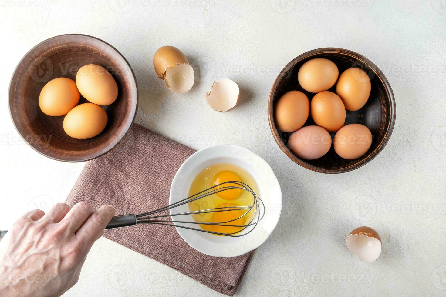 A woman's hand is beating eggs with a whisk on the kitchen table