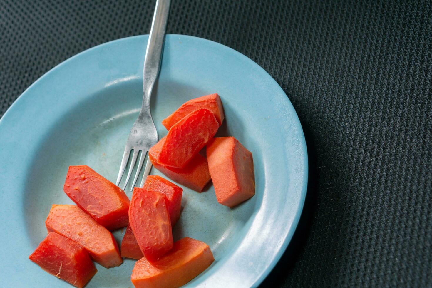 Closeup of fresh red papaya fruit on a plate with a fork photo