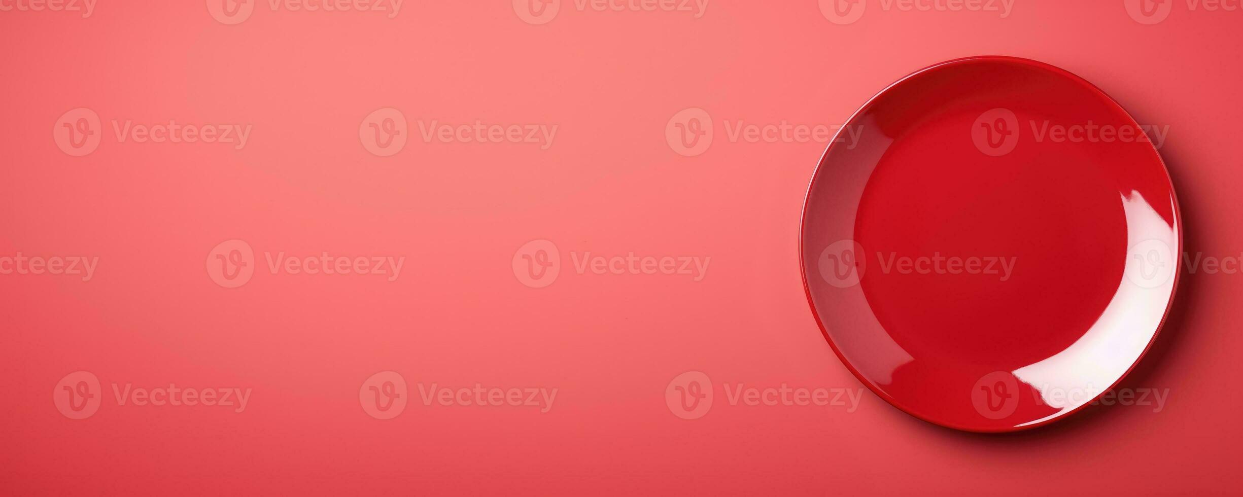 Vivid red round plate isolated on red background with a copy space, top view photo