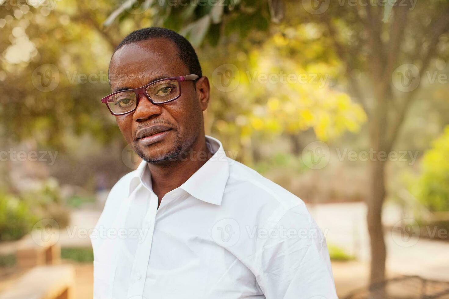 serious african man looking at camera standing in a park photo