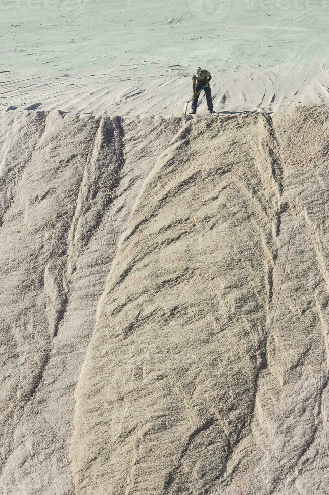 Worker shoveling bulk salt, Salinas Grandes de Hidalgo, La Pampa, Argentina. photo