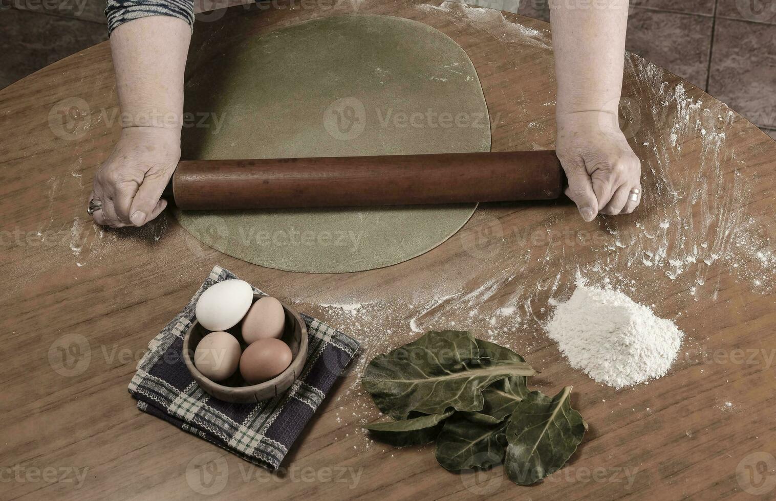 Grandma's hands kneading, dough for green noodles. photo