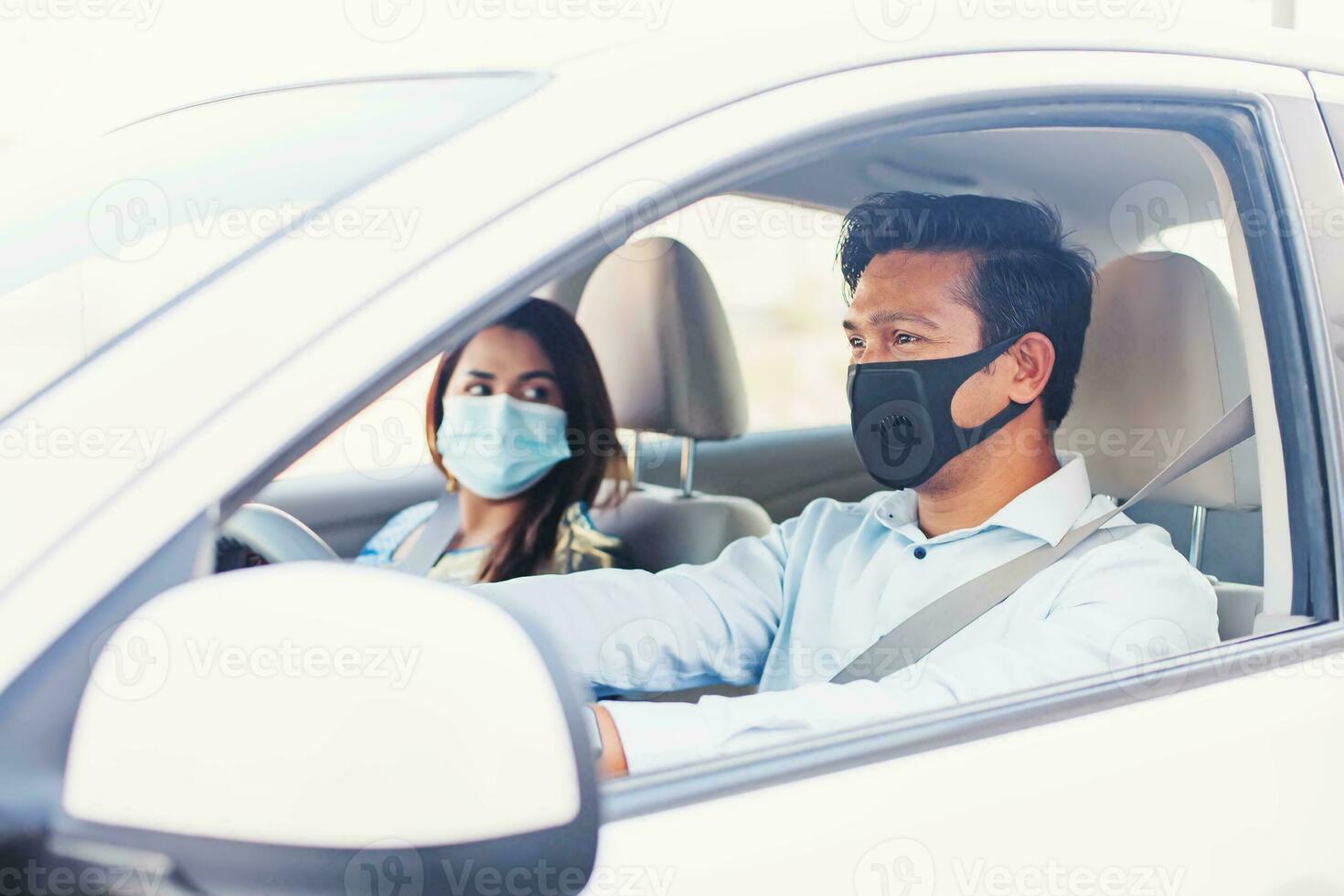 a man and woman wearing face masks while driving a car 26413930 Stock