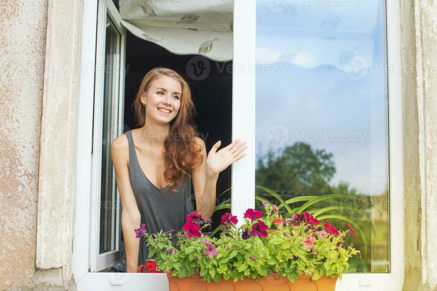 a woman is smiling and waving from a window photo