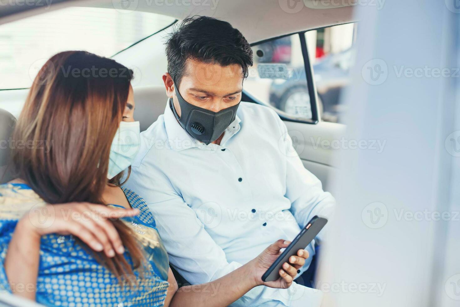 Indian couple wearing face medical masks taking a cab and using mobile phone app for booking photo