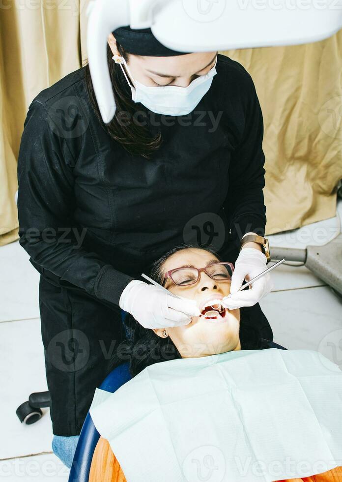 dentista examinando boca a paciente, mujer dentista haciendo endodoncia a mujer paciente, mujer dentista con paciente acostado abajo, dentista ejecutando estomatología foto