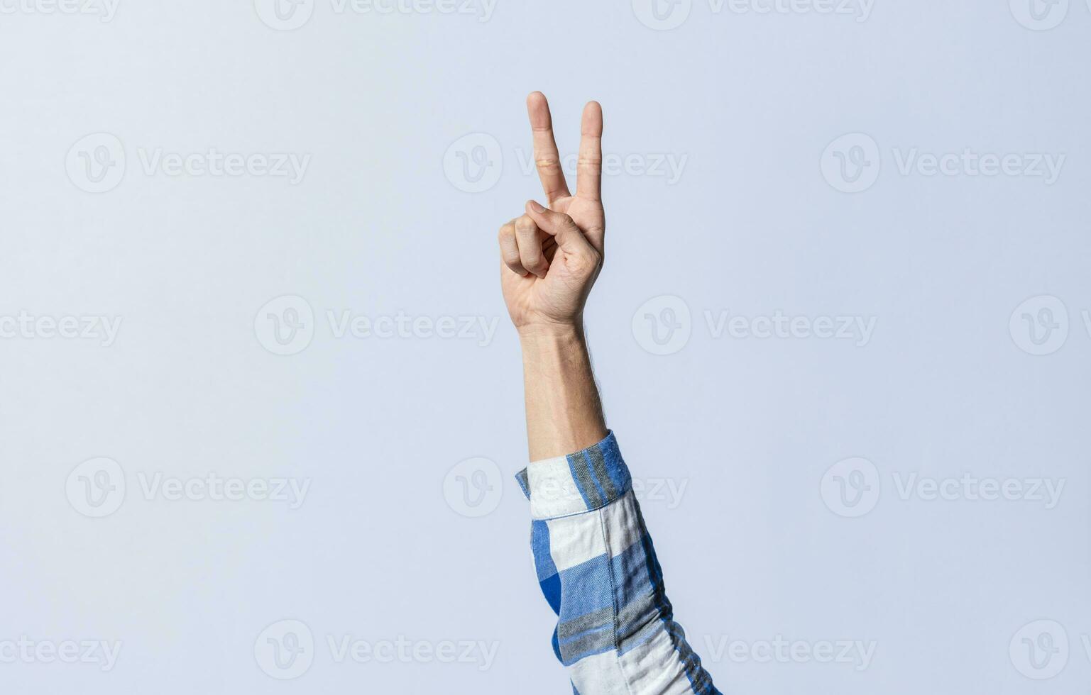 Hand gesturing the letter V in sign language on an isolated background. Man's hand gesturing the letter V of the alphabet isolated. Letter V of the alphabet in sign language photo