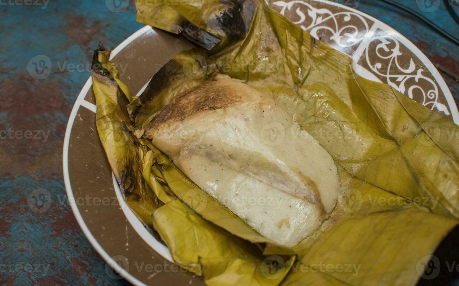 Stuffed tamale served on wooden table, stuffed tamale on banana leaf served on wooden table, typical nicaragua food photo