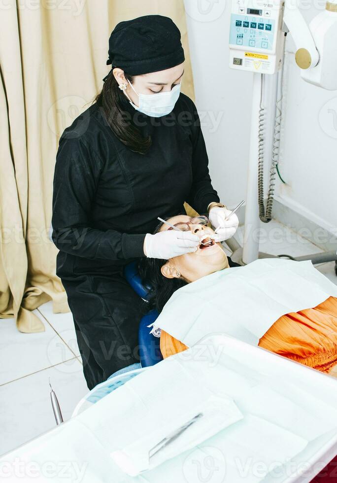 dentista con paciente acostado abajo, dentista examinando boca a paciente, mujer dentista haciendo endodoncia a mujer paciente, dentista ejecutando estomatología foto