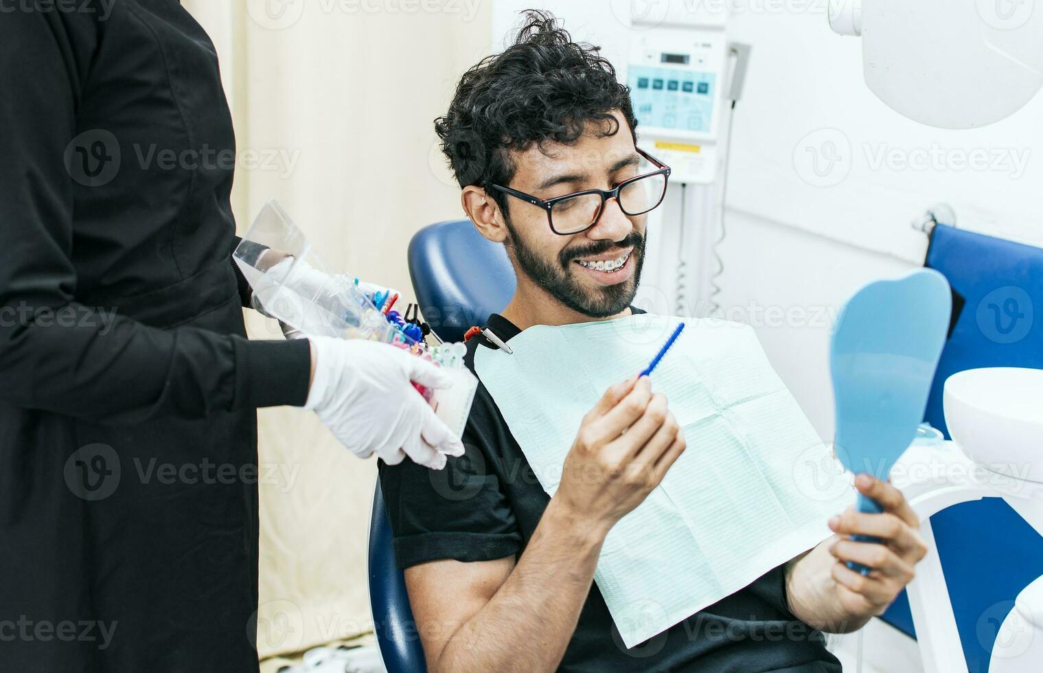 Patient with dentist choosing dental braces, Dentist with patient choosing metal braces, Patient with dentist choosing rubber band photo