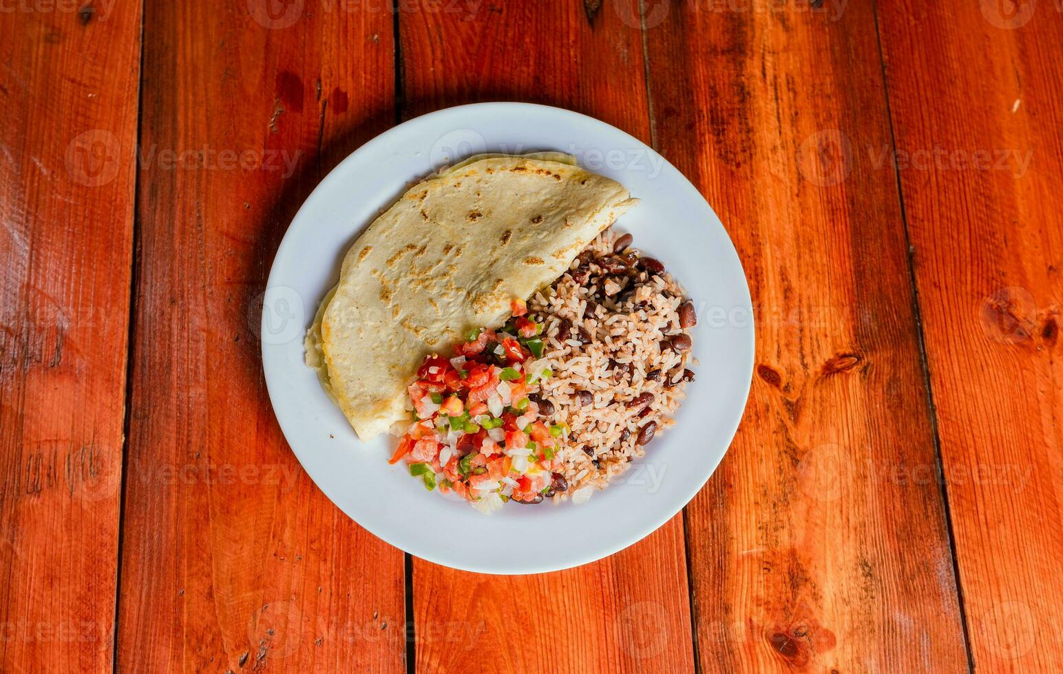 Quesillo dish with gallo pinto and pico de gallo on wooden table. Nicaraguan food Gallo pinto with pico de gallo and Quesillo served photo