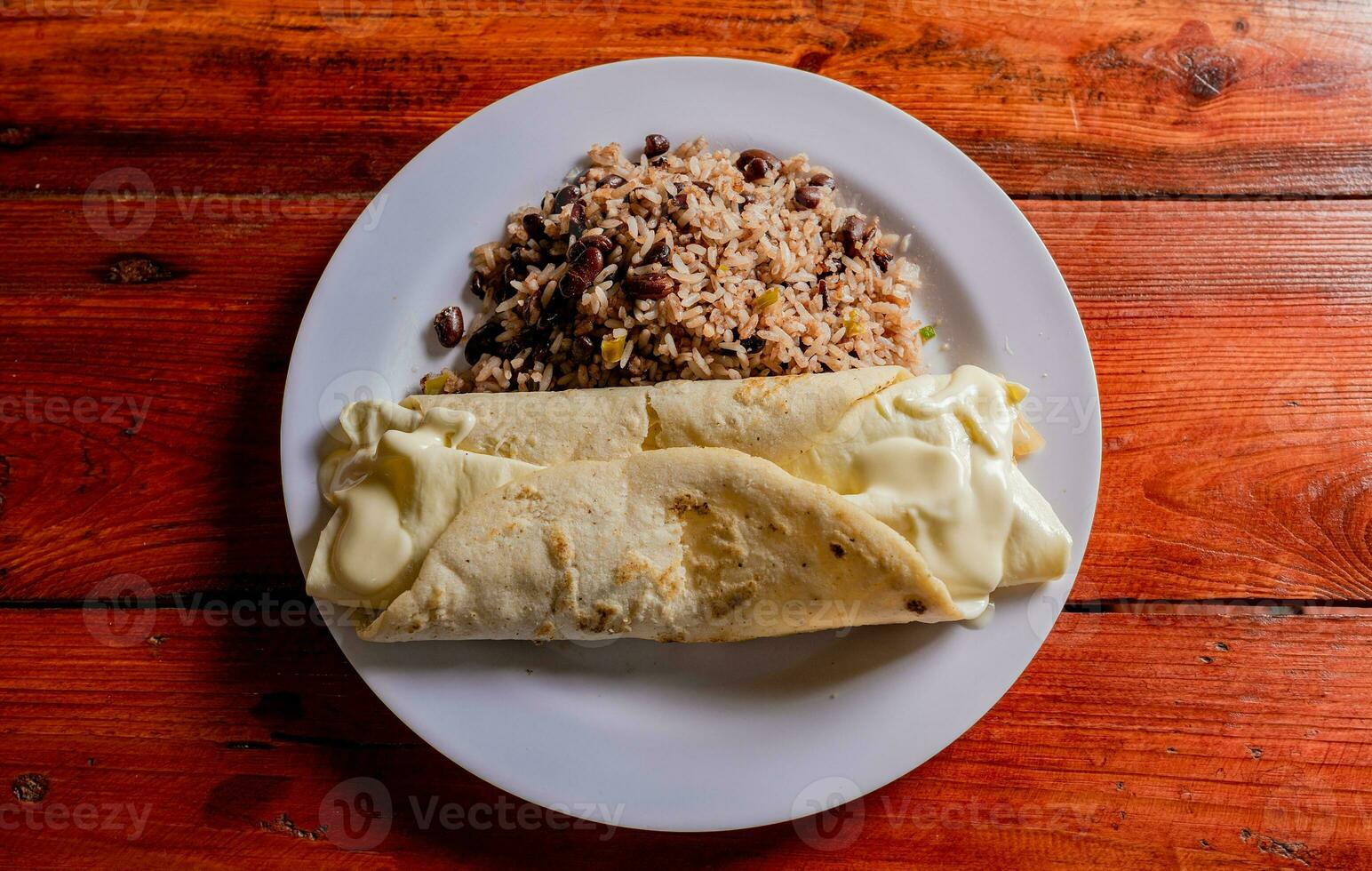 parte superior ver de tradicional gallo caballo pinto con quesillo servido en de madera mesa. plato de nicaragüense gallopinto con quesillo en el mesa. típico nicaragüense comidas foto