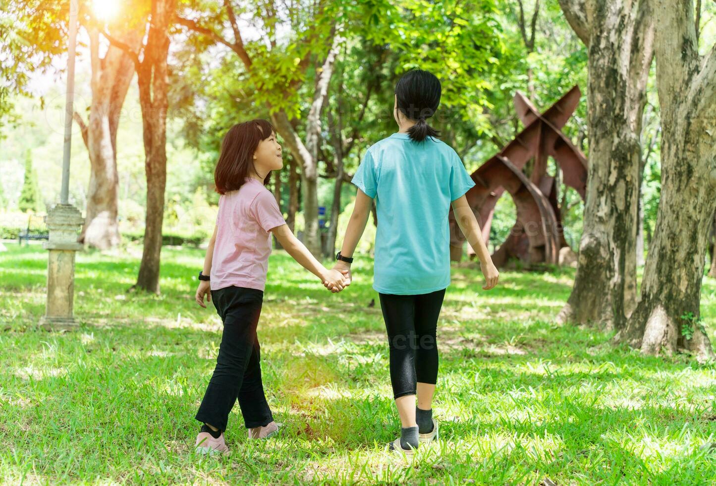 Two sister holding hands in the park in warm spring day. Happy friendship family concept. photo