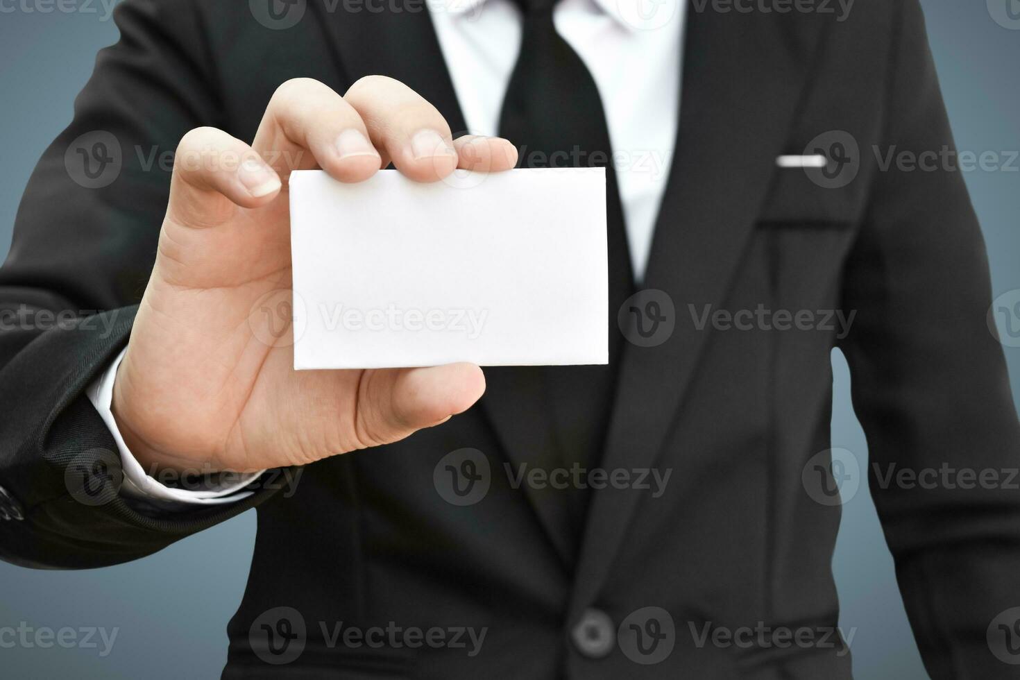 Businessman showing white piece of paper in black suit. Idea for business credit card or visiting card. photo