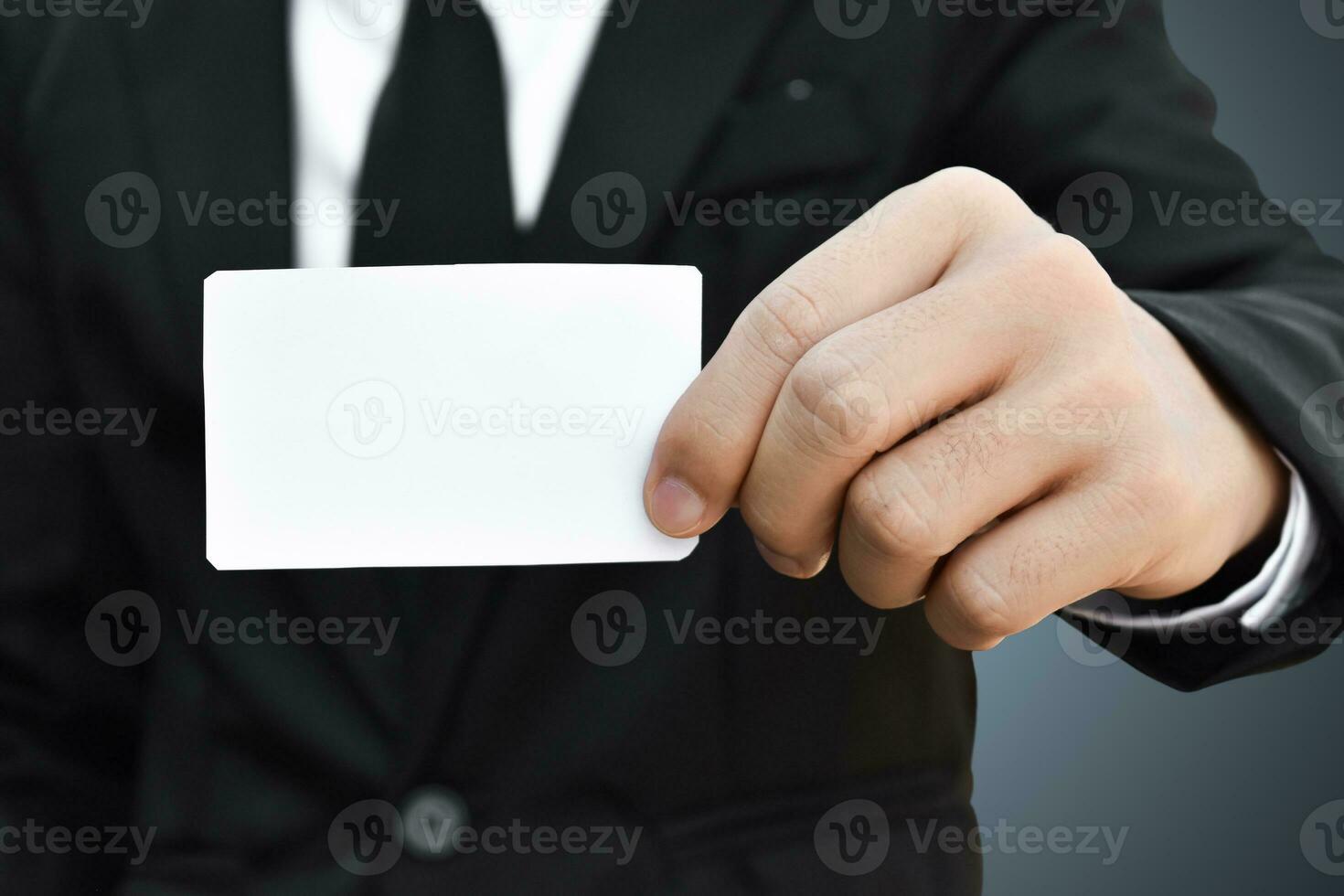 Closeup of businessman who takes out white piece of paper from the pocket in black suit. Idea for business credit card or visiting card. photo