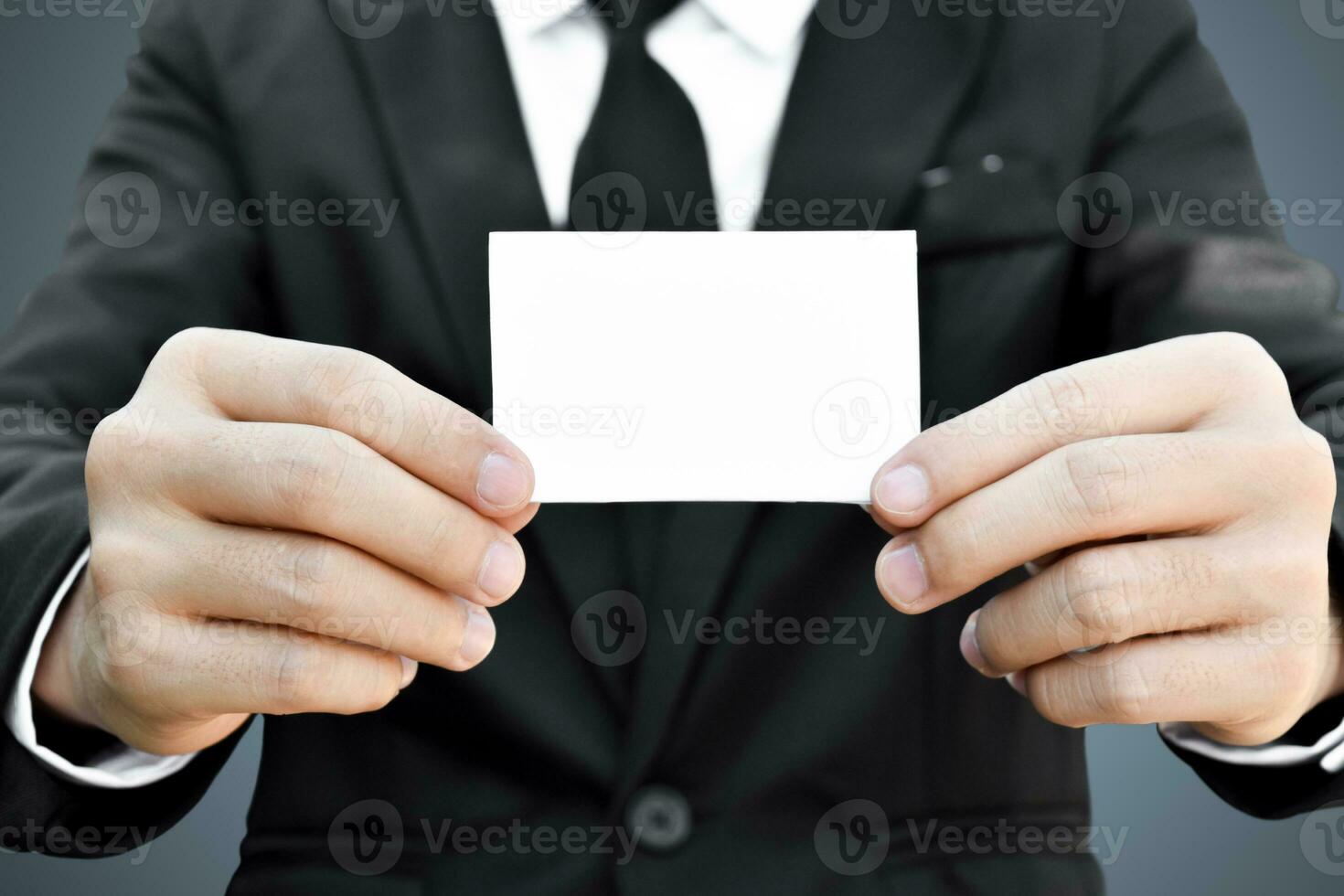 Closeup of businessman who takes out white piece of paper from the pocket in black suit. Idea for business credit card or visiting card. photo