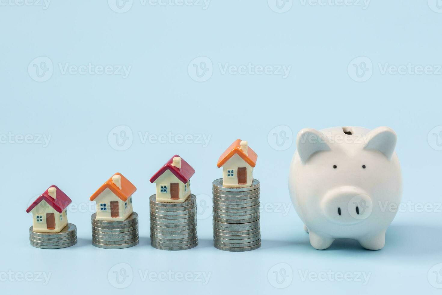 Mini house on stack of coins on a blue background. Concept of Investment property, Real estate, Saving money. photo