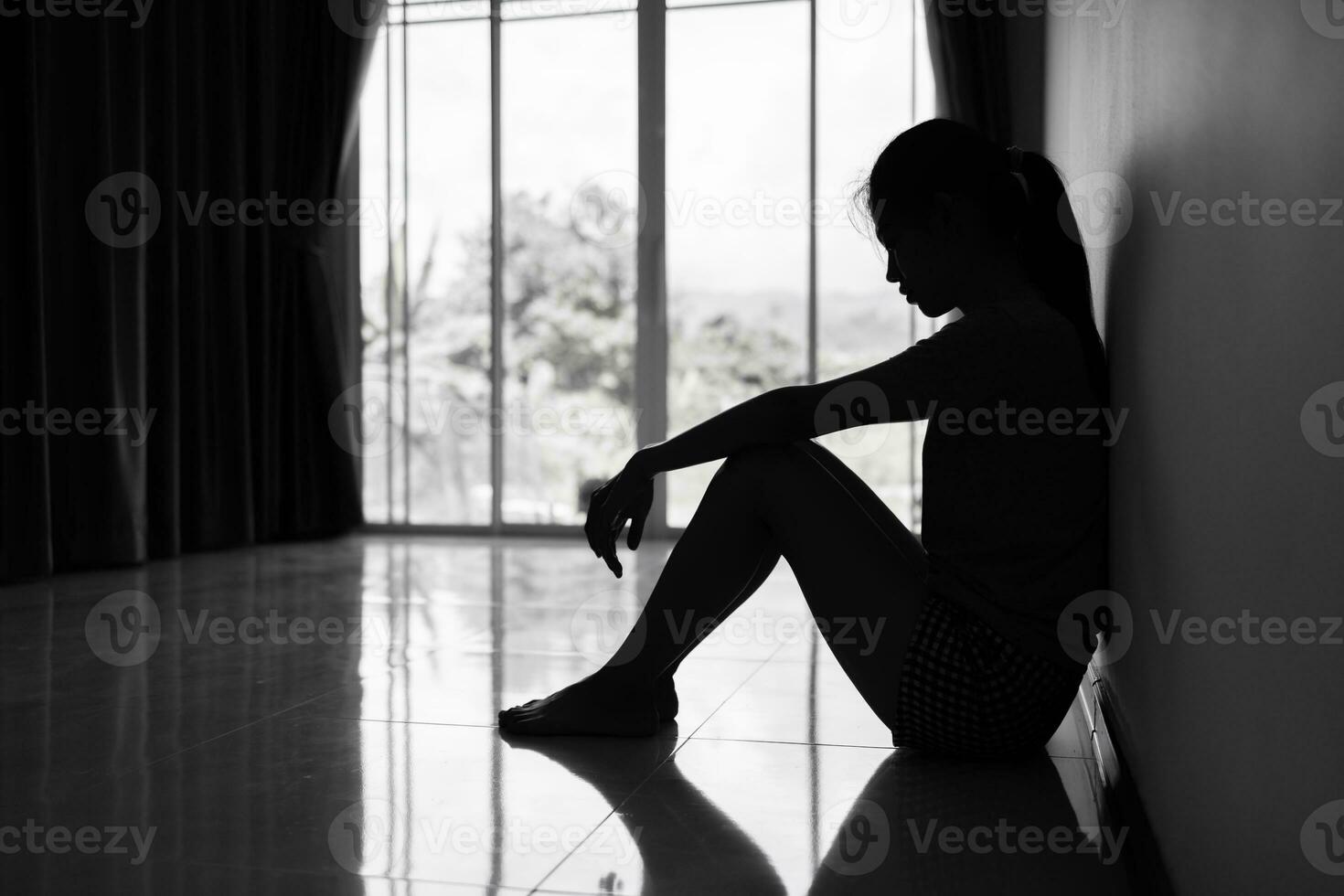 Silhouette of Depressed young woman near window at home, closeup in the dark room. domestic violence, violence against womenBlack and white photo. photo