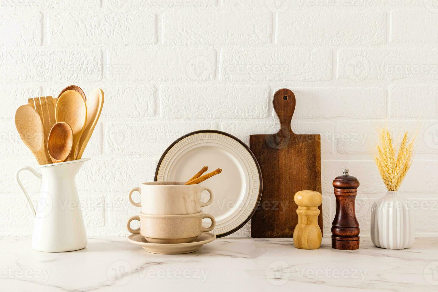 Front view of a kitchen marble countertop with a set of kitchen utensils and utensils against a white brick wall. Cozy kitchen. photo