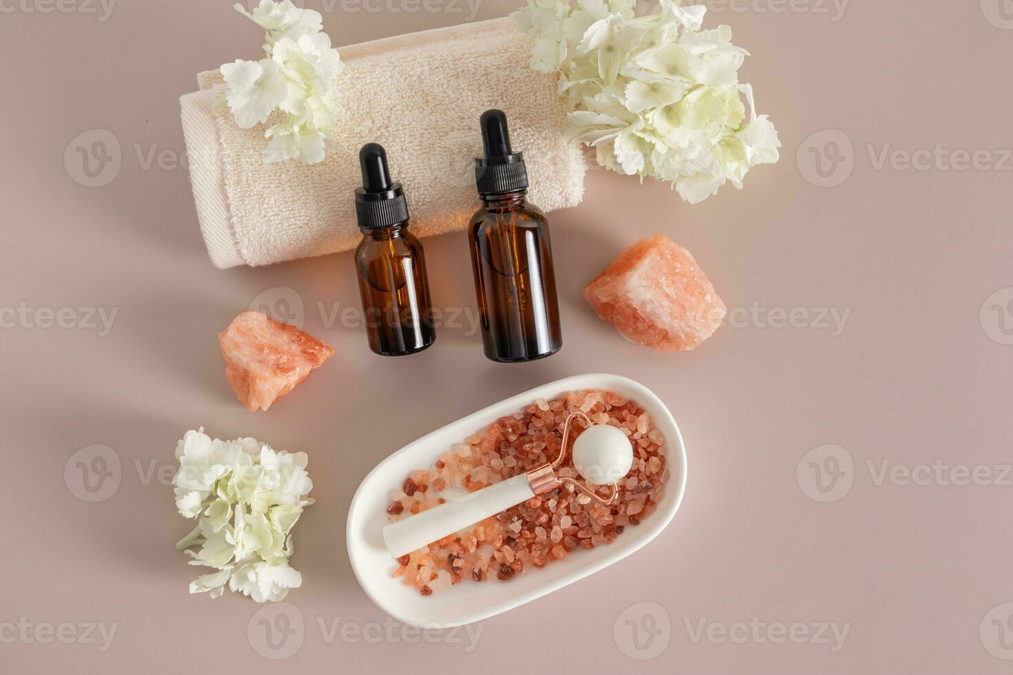 A two bottle of cosmetic product on the roller of the towel , white stone massager in an oval bowl with bath salts. Top view . A copy space. photo
